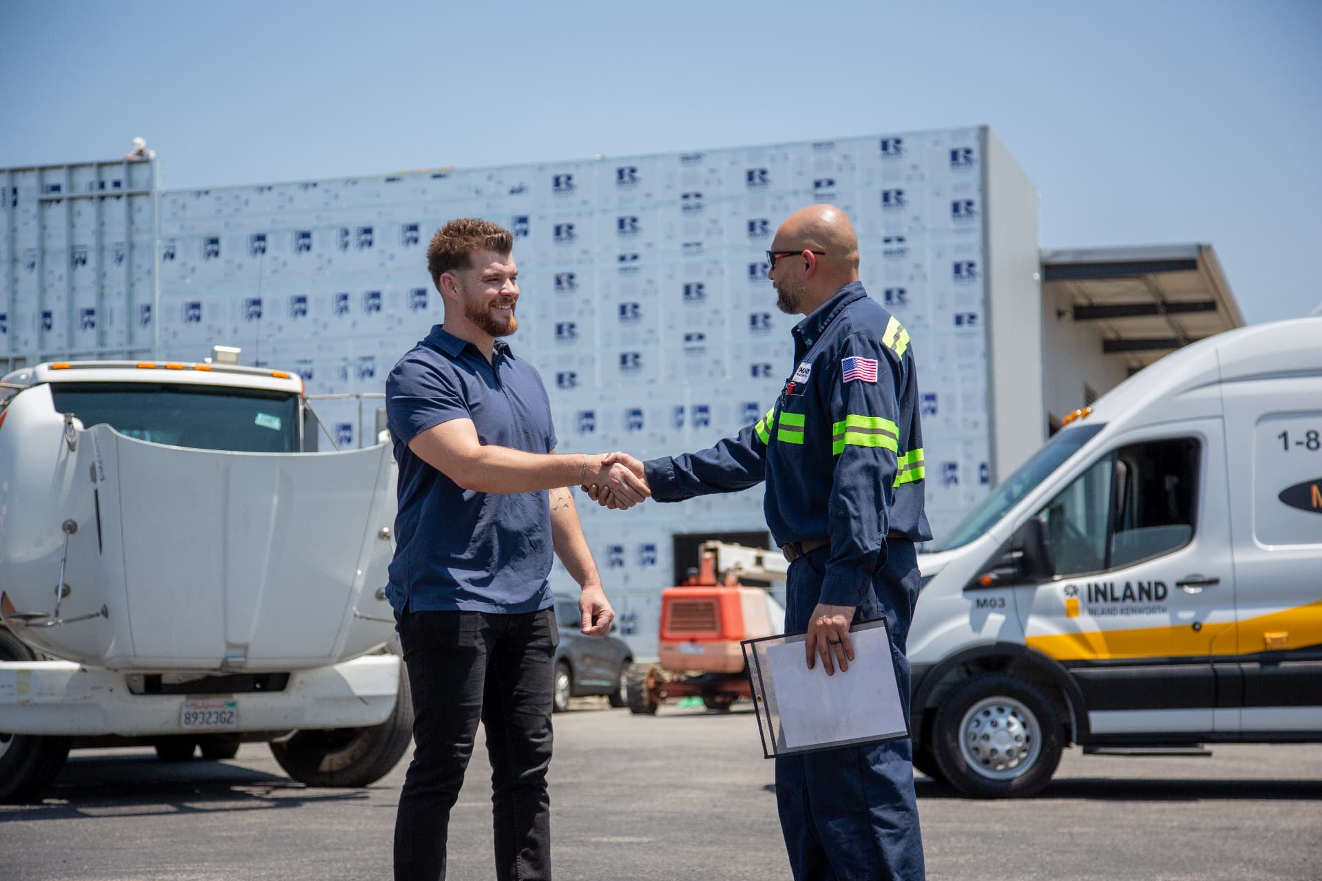 Inland Truck & Equipment service technician shaking hands with a client beside a branded service vehicle — corporate video and brand video production